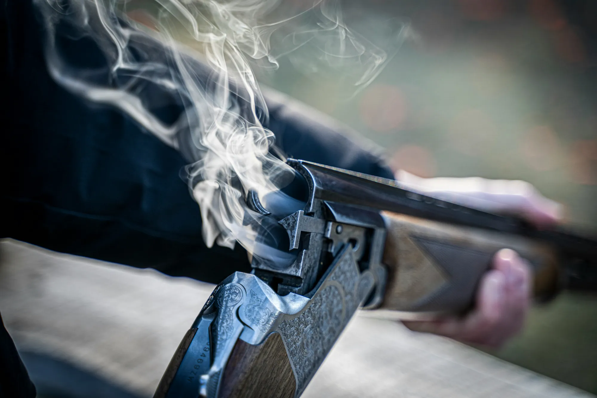 A double-barrelled shotgun just broken open, smoke rising from the breech